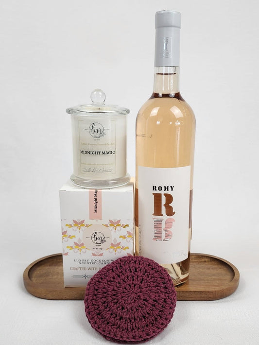 Wine bottle labeled 'Romy' with a glass carafe and wooden tray with crochet coasters on a white background